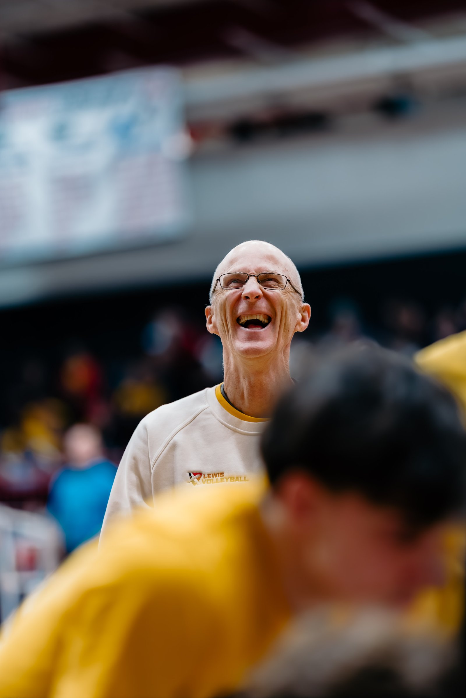 A Lewis volleyball coach laughs during a match.