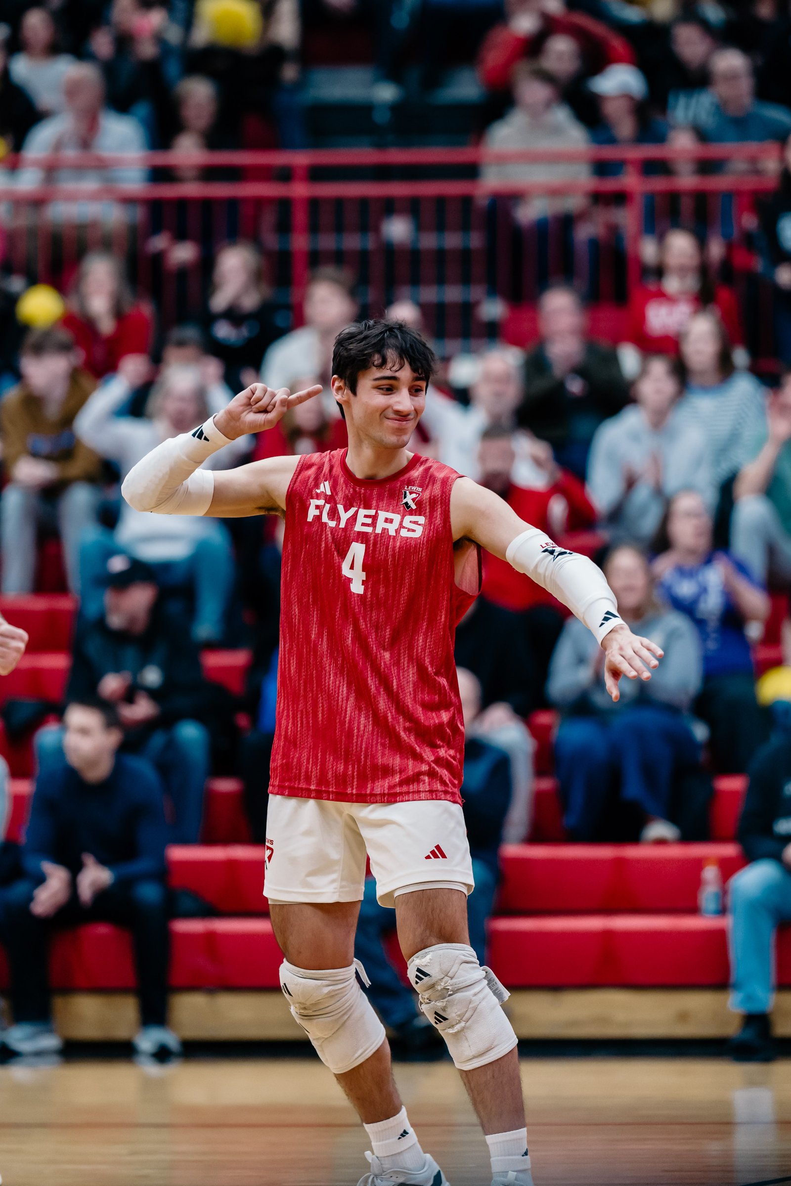 A male volleyball player in a red jersey with number 4 celebrates on the court.