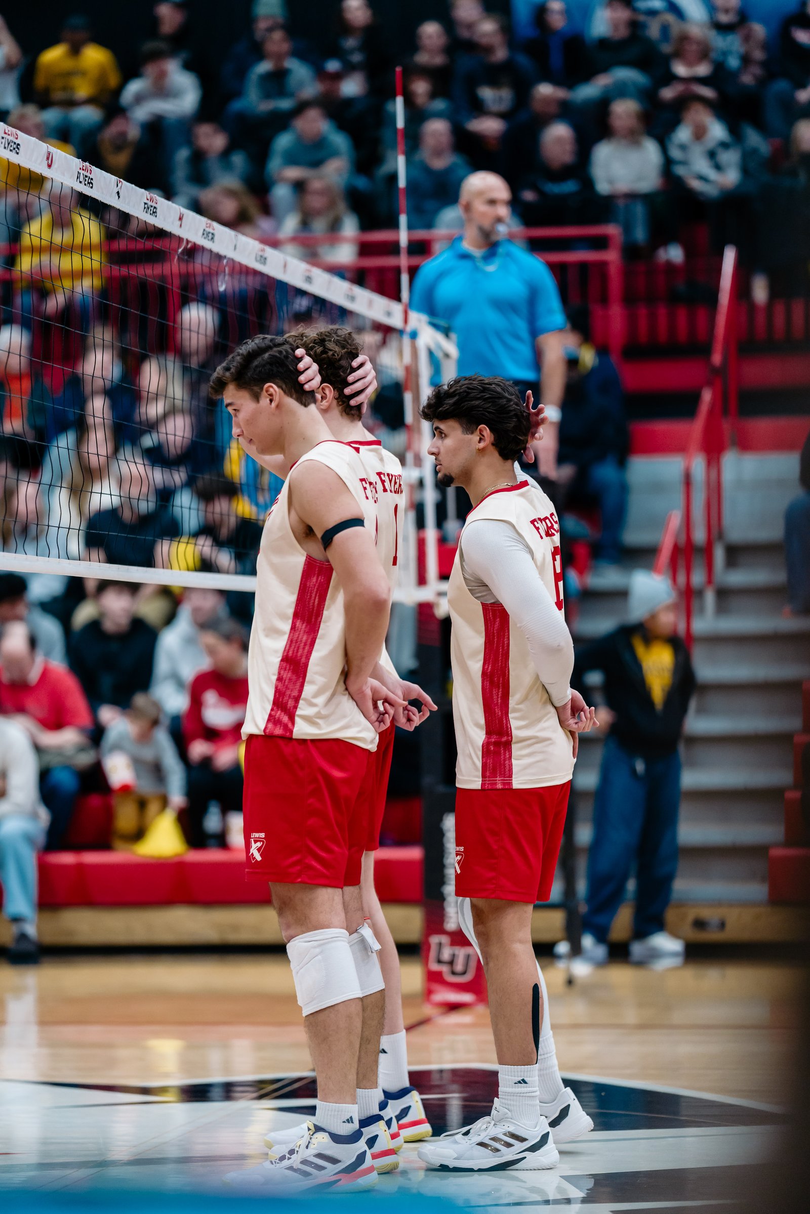 Lewis Flyers players in red and cream uniforms stand on the court during a match.