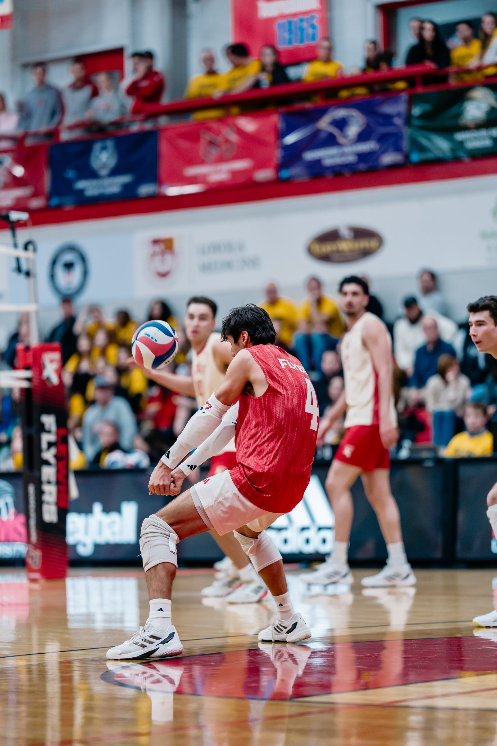A volleyball player in a red jersey with number 4 makes a pass during a game.