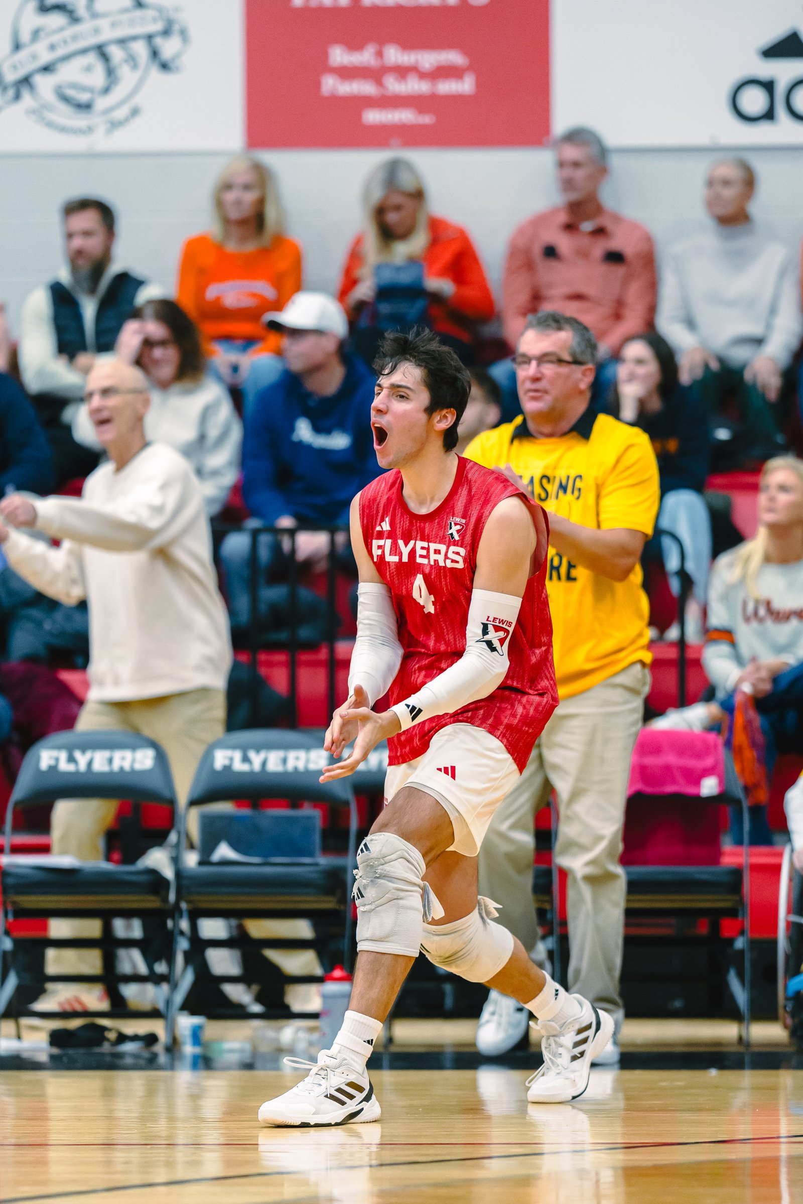 A Lewis Flyers volleyball player in a red jersey with number 4 yells during a game.
