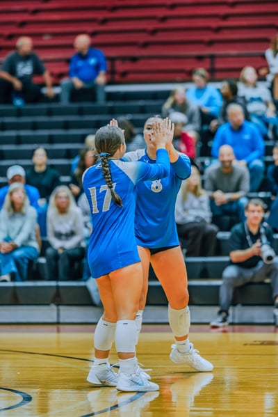Players 17 and 8 in blue high-five on the court during a game.