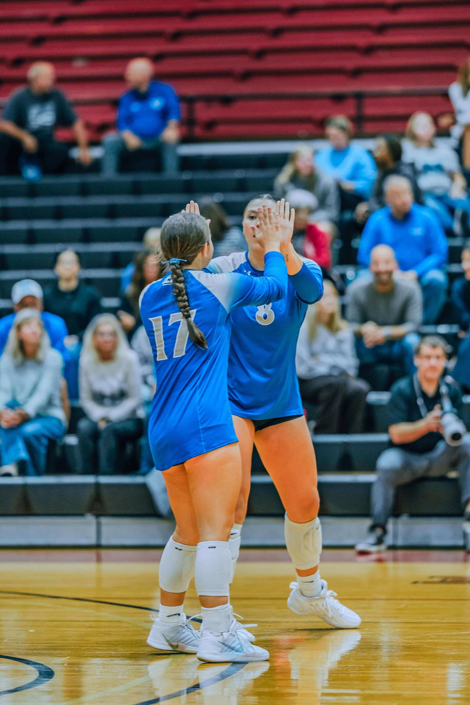 Players 17 and 8 in blue high-five on the court during a game.