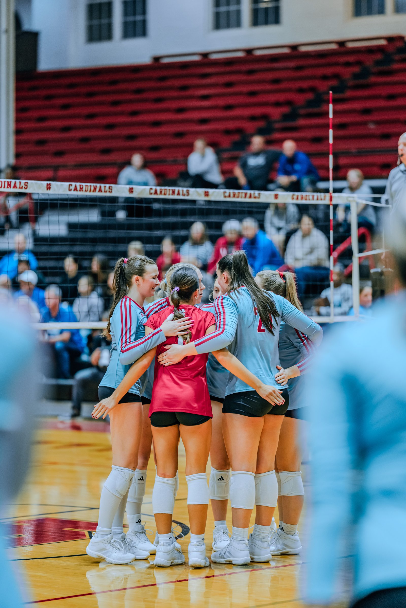 Players in light blue and red jerseys huddle together on the court, with a player in red jersey number 5 in the center.