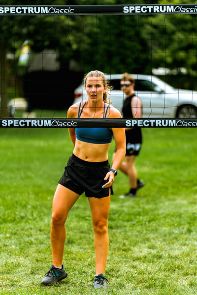 A player in a blue top and black shorts stands with her hands behind her back.