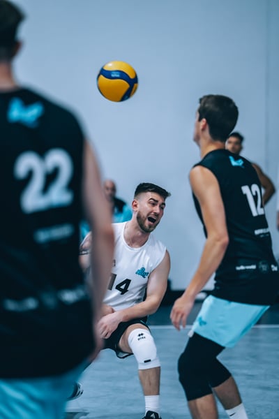 A player in white crouches as a player in black moves toward the ball.