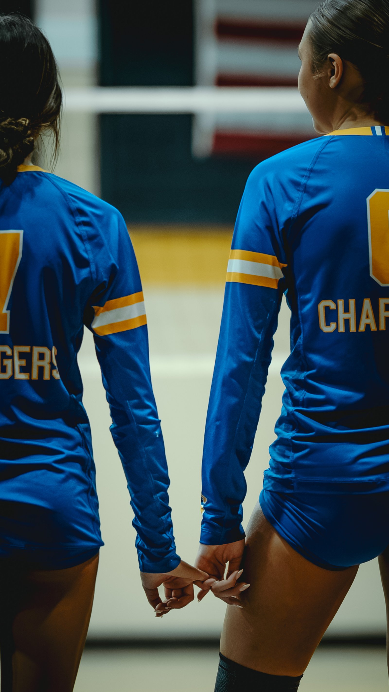 Two players in blue jerseys hold hands, one with jersey number 7 and the other with "CHARGERS" visible.