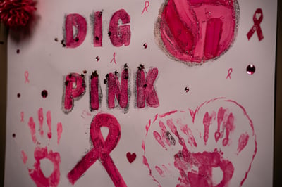 A pink pom-pom is in the upper left corner of a poster with the words DIG PINK written in glittery pink letters.