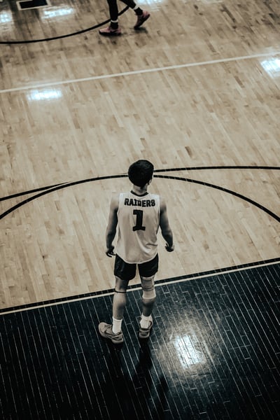 A player in a white jersey stands on a basketball court.