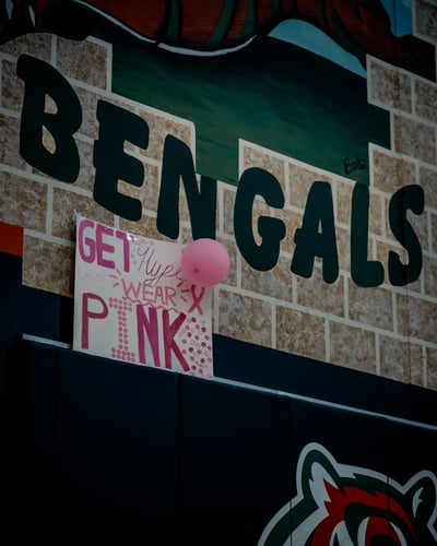 A pink balloon floats near a sign on a brick wall.