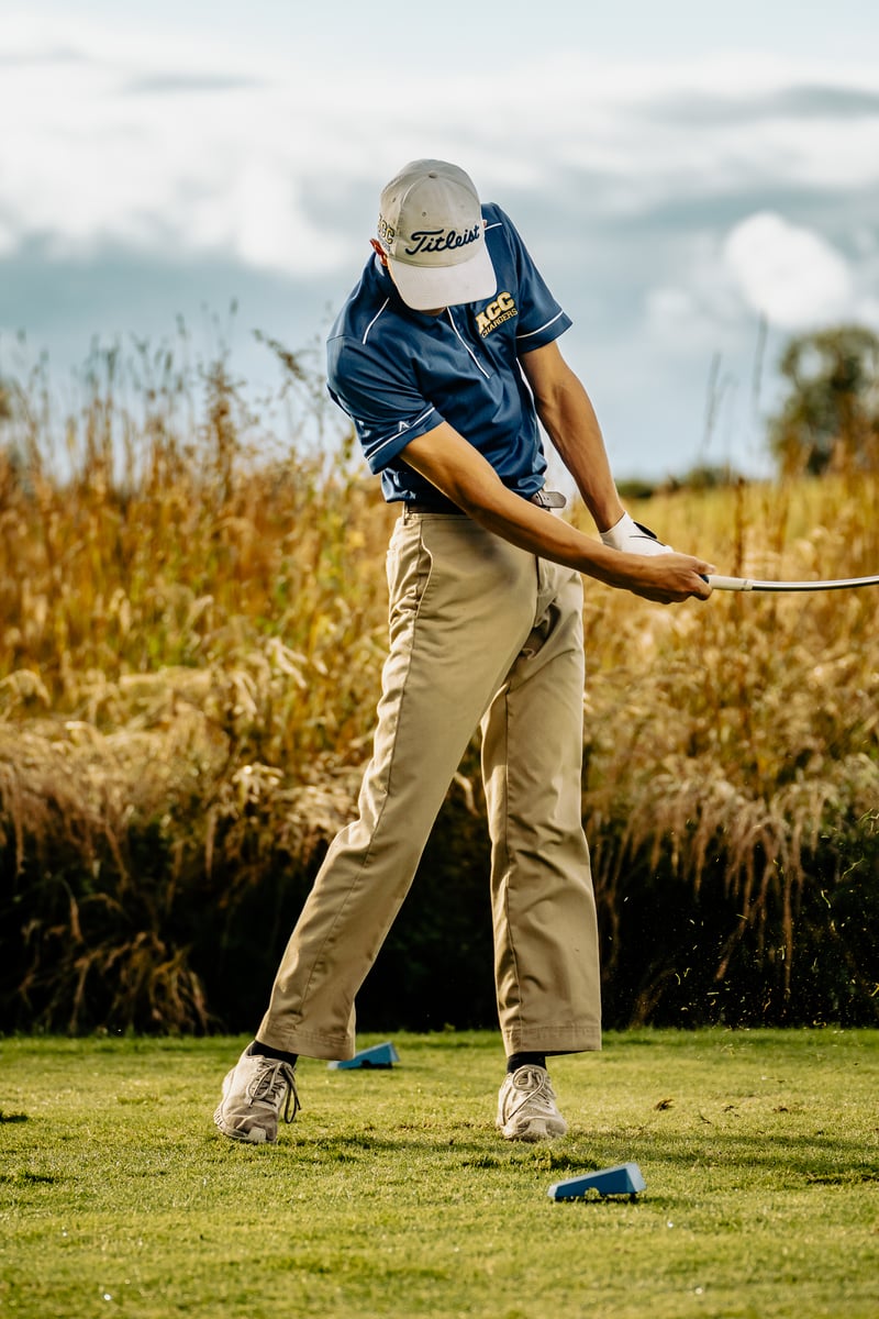 A golfer swinging from tall grass