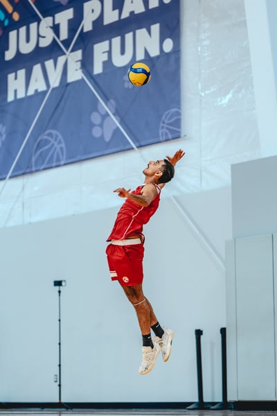A player in red jumps with arms extended.