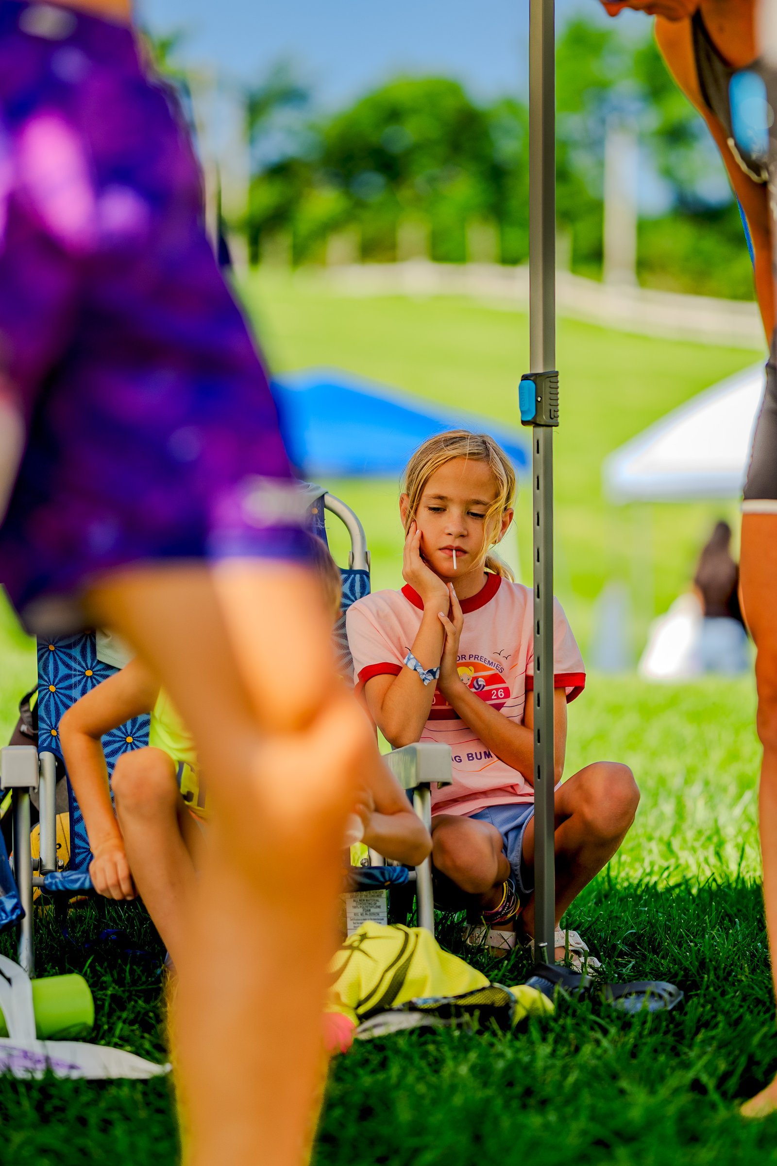 A player in a pink top with red trim and blue shorts sits with a lollipop, while another player in a yellow top is visible in the foreground.
