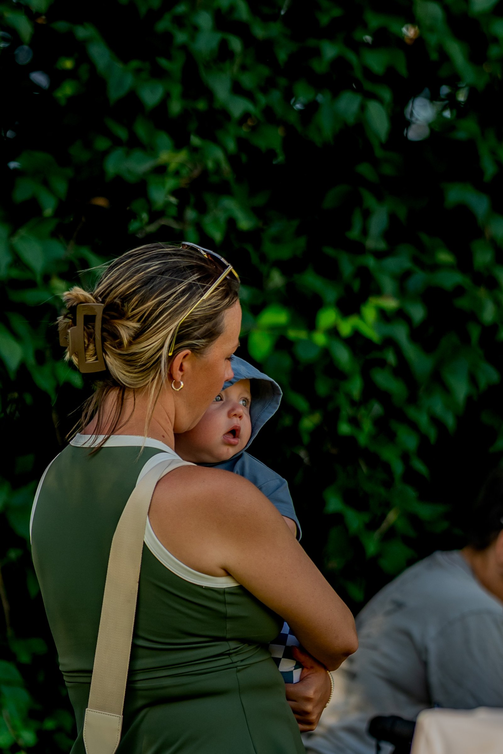 A player in a green top holds a baby while another player in a gray shirt sits nearby.