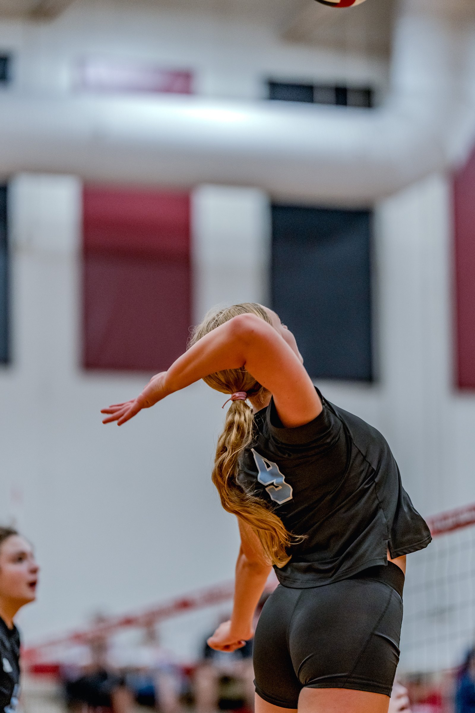 A player in a black top with a light blue number 4 prepares to hit a volleyball during a game.