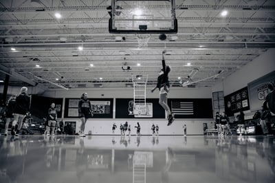 A player in dark uniform jumps toward the basket with the ball.