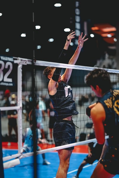 A player in black jumps with arms raised, while a player in yellow and black stands facing him.