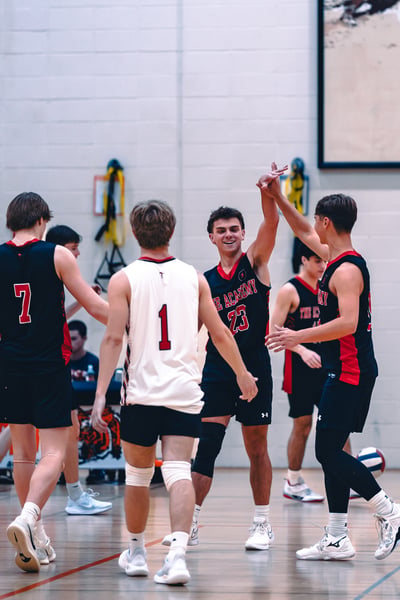 A player in black and red high-fives a player in white and red on a court.