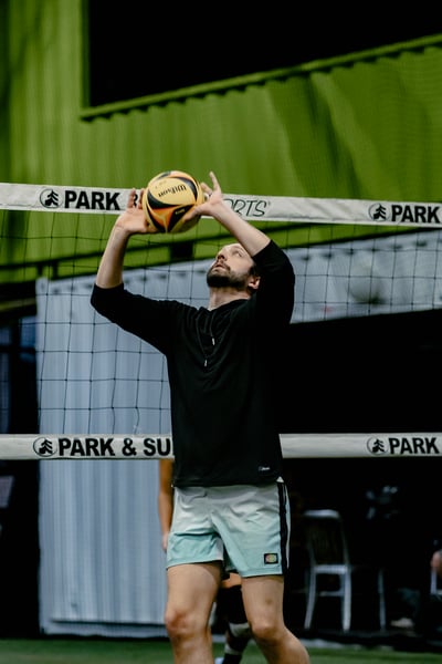 A player in black reaches overhead for the ball.