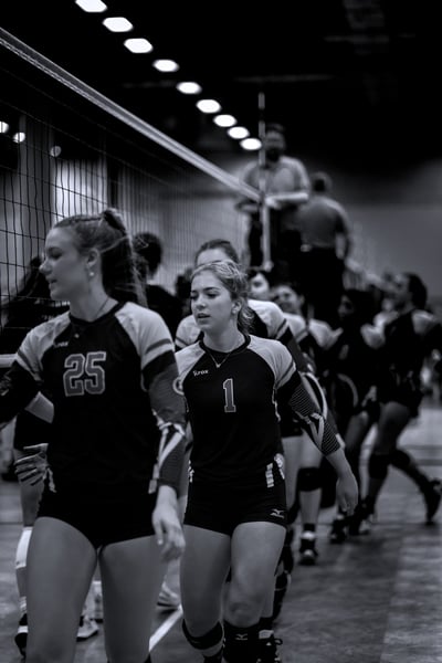 A player in black and gray walks forward with her left hand extended.