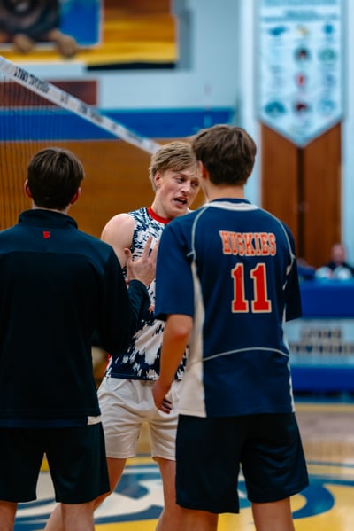 A player in a blue uniform talks to a player in a white and blue patterned uniform.