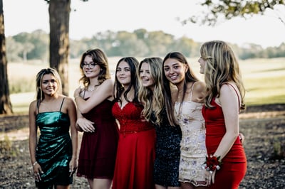 Six people stand together outdoors, smiling and looking in different directions.