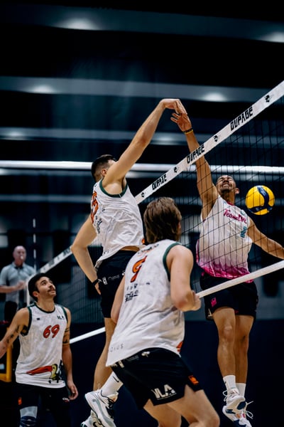 A player in a white and pink top reaches for the ball over the net.