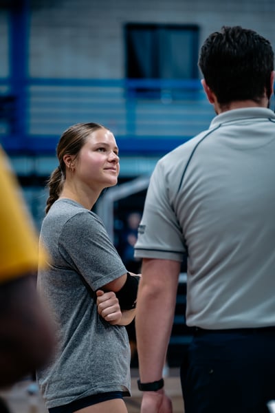 A player in a gray shirt crosses her arms and looks to the side.