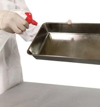 A laboratory personnel spraying and cleaning the interior components of an incubator