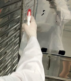 A laboratory personnel spraying the inside of incubator to clean it