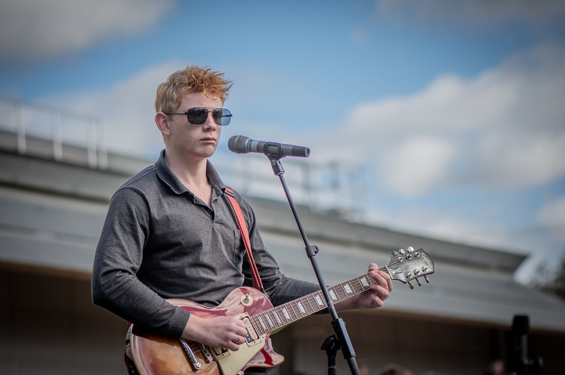 Ashton Jude performing on stage with guitar under dramatic lighting