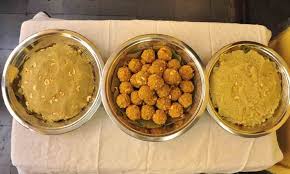 Hand holding a temple prasadam laddu