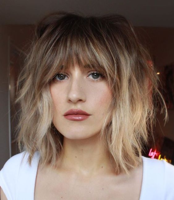 In this image show, the Textured Bangs for Thin wolf haircuts with add some blonde highlights. 