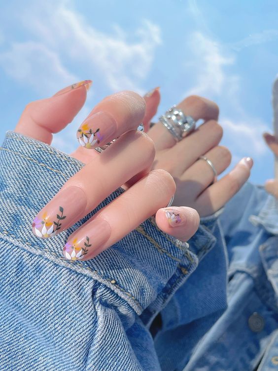 In this image show, the cute mid-length elegant spring nails with a twist of flower print in this base of pink color nail manicure.