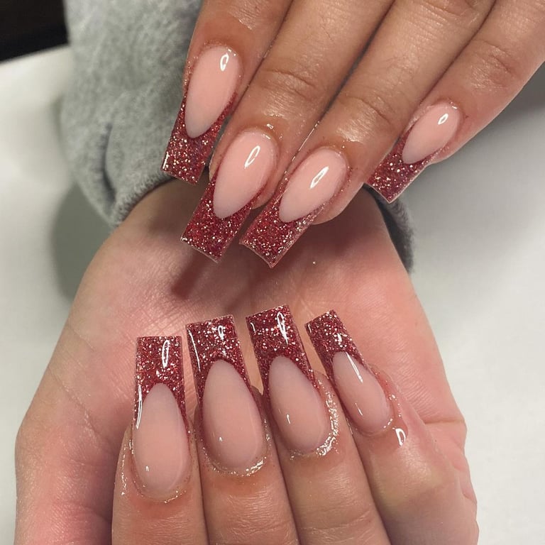 In this image show, the long cute nude with red glitter frinch tip of nails design.