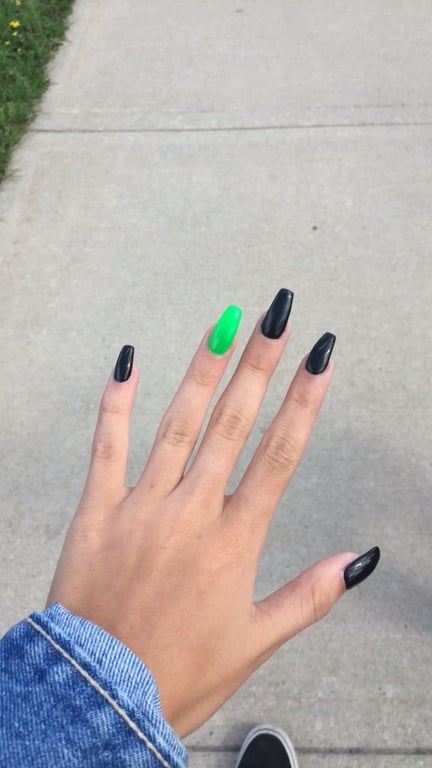 In this image show, the green and black combination of nails while showing a single hand pose nails.