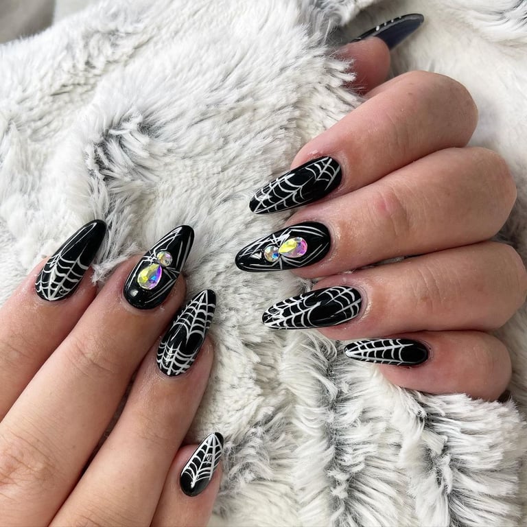 In this image show, the black color with spider and ringstone nails art.