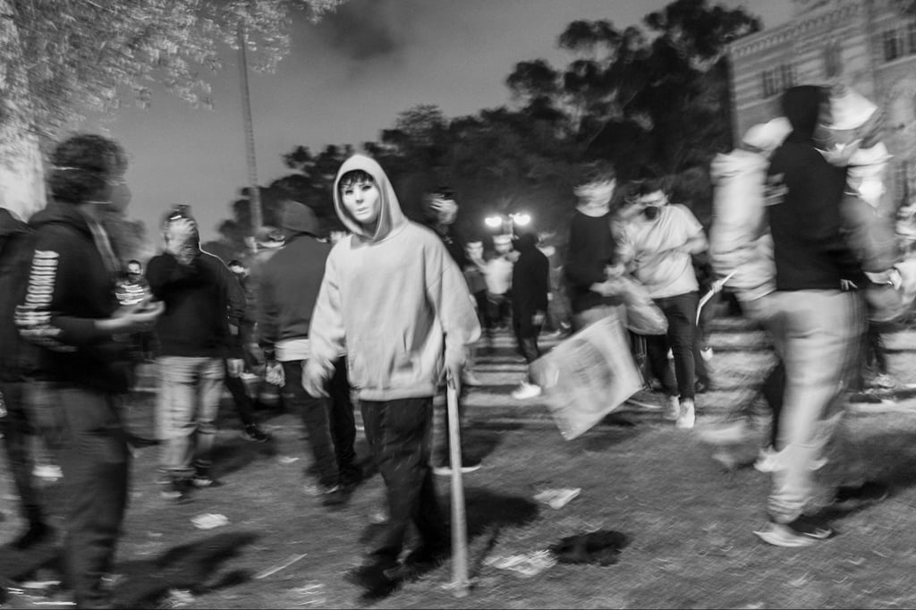 Someone in a mask walks around the UCLA encampment. 