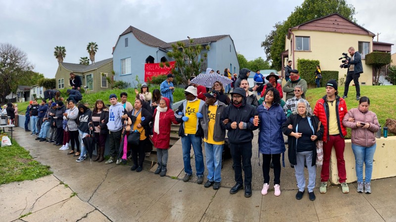People lock arms in front of vacant Caltrans-owned homes occupied by a group of unhoused and housing-insecure families in the northeast LA neighborhood of El Sereno in March 2020.