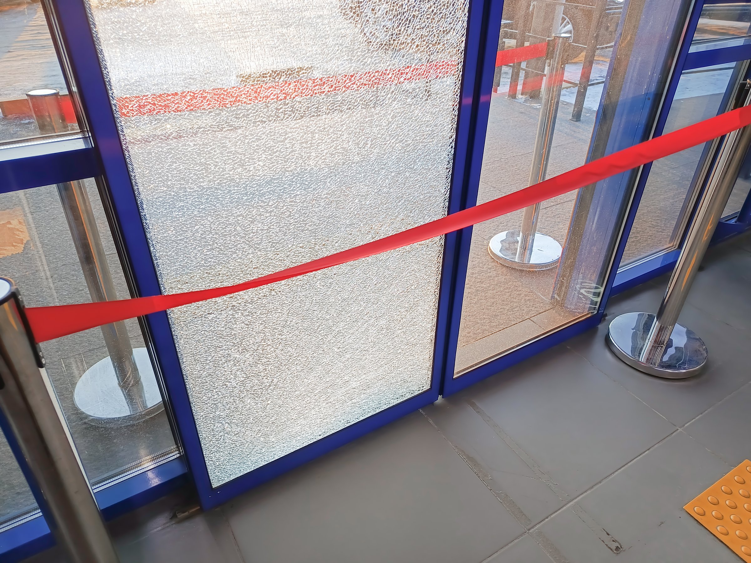 The broken glass on the automatic sliding door is protected by red tape. Repair of automatic doors.