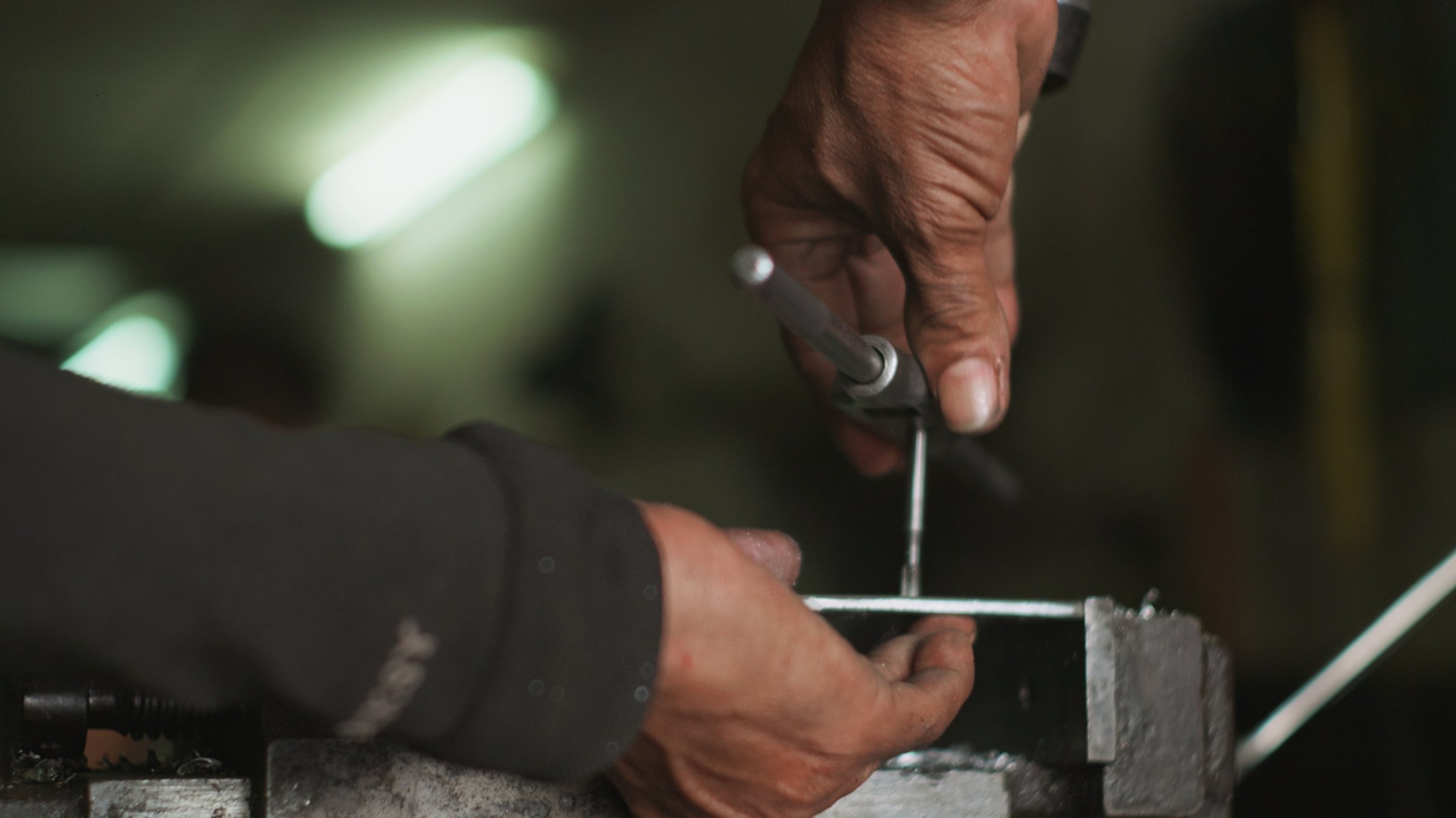 Elderly Asian machinist working in a metal workshop using a milling machine to create precision aluminum parts.