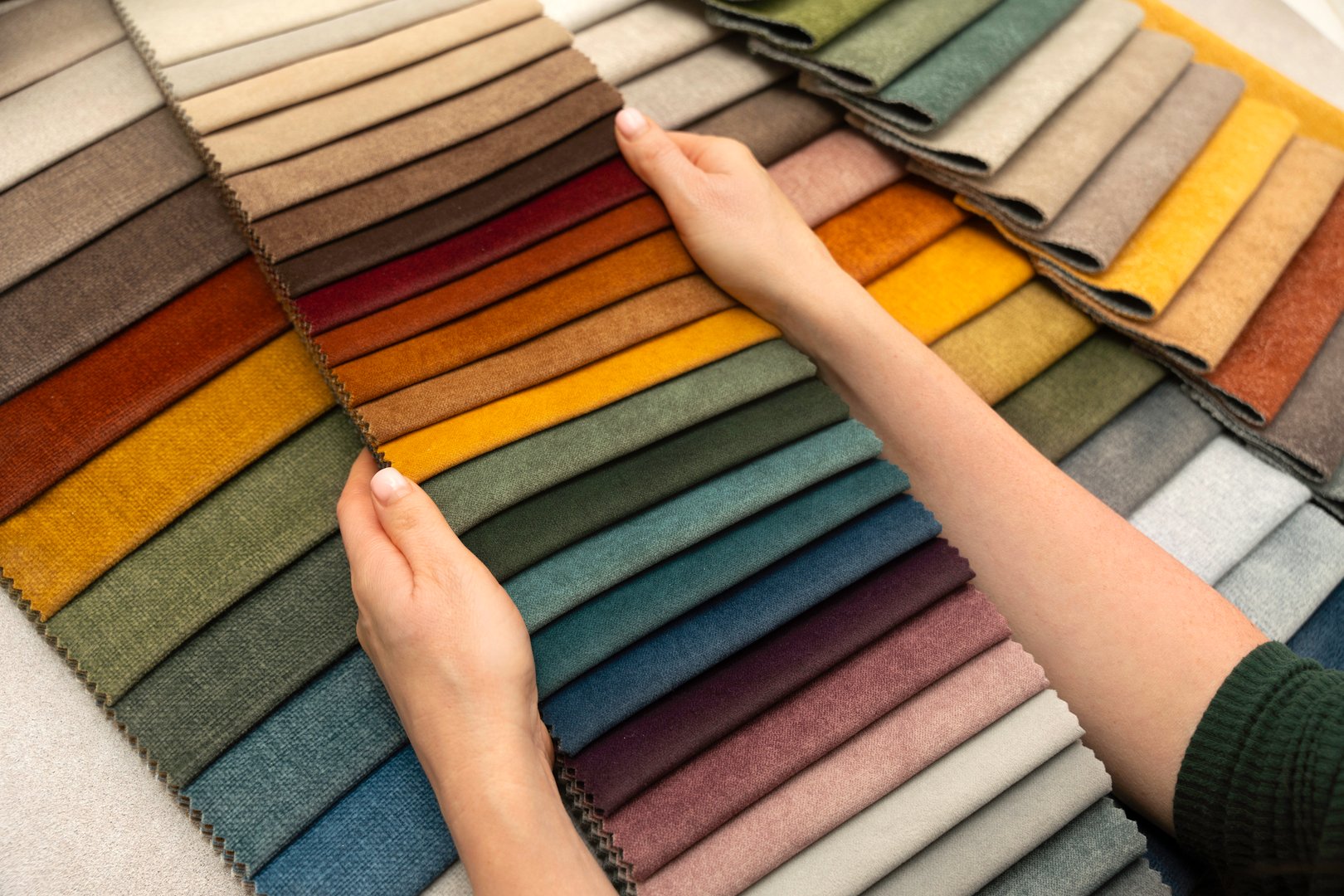 Hands holding fabric swatches for custom furniture and upholstery, textile samples for interior design, home decoration and creative material selection.
