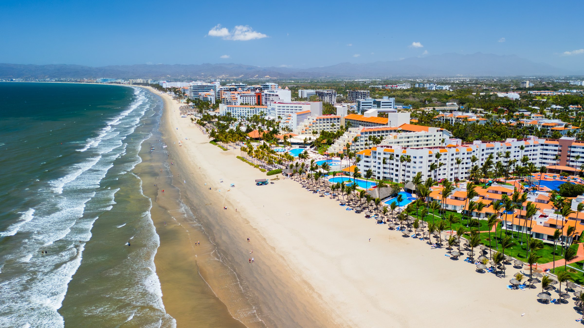 Aerial view of luxury hotels, resorts, and swimming pools lining the sandy beach in nuevo vallarta, mexico