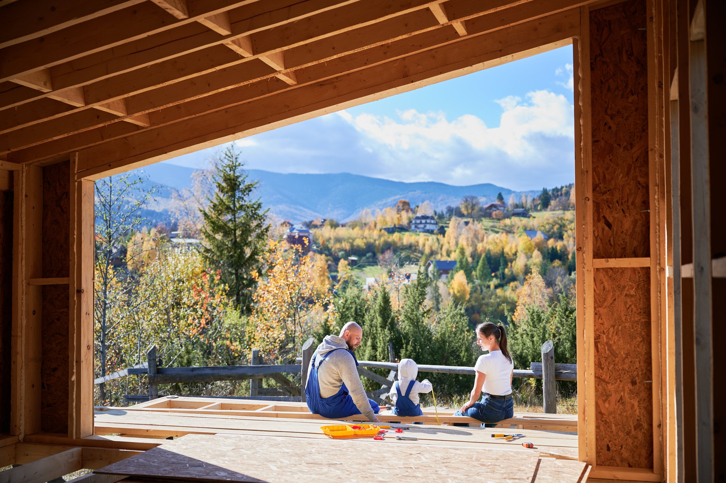 Father, mother and son building wooden frame house
