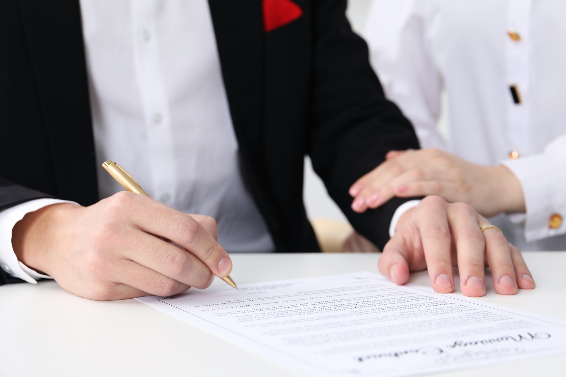 Newlyweds signing marriage contract at desk, closeup