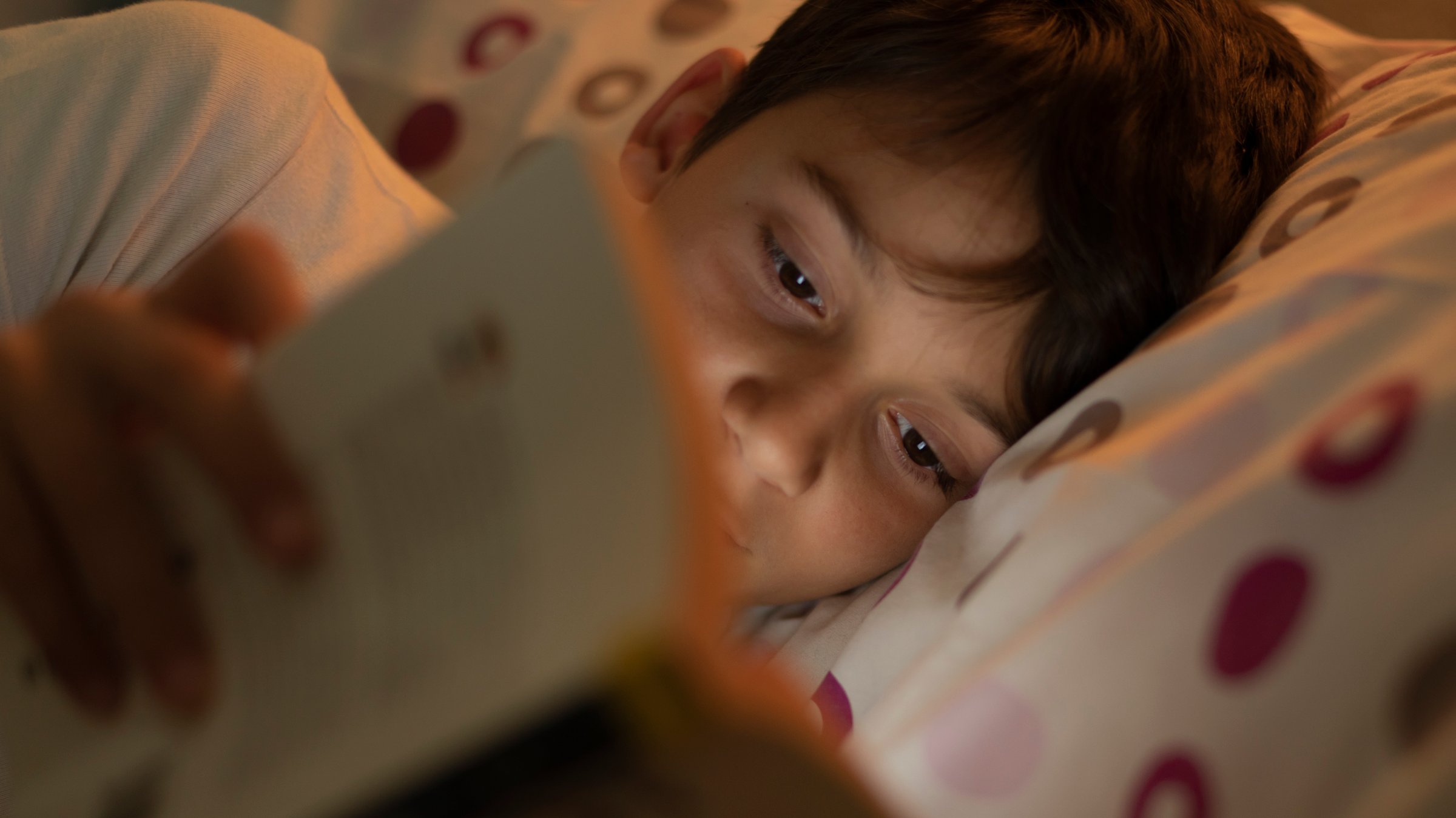 boy reading a book in bed at night before sleeping