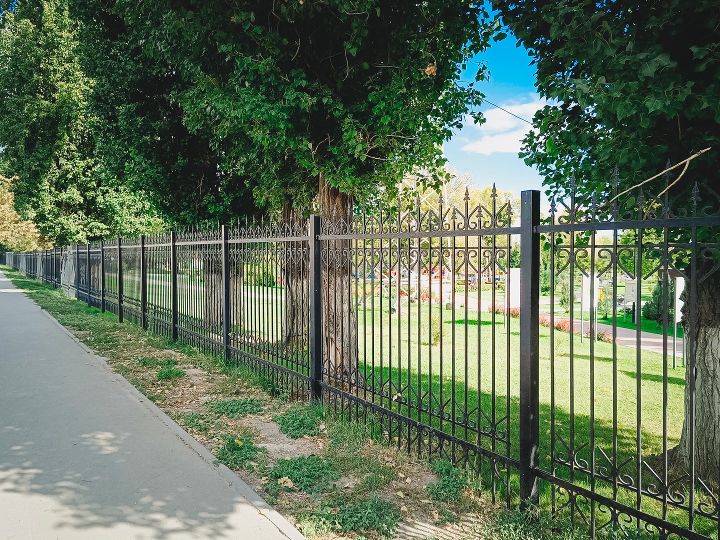 A black metal fence along the sidewalk on a city street.