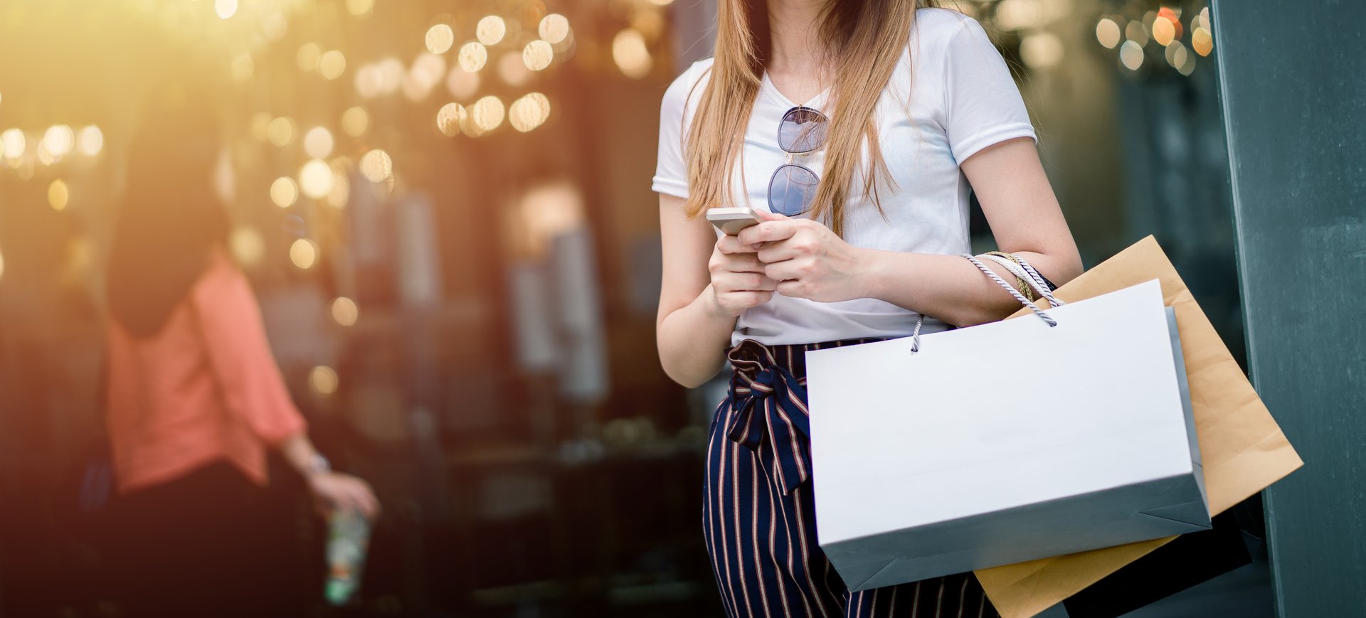 Beautiful girl long hair She is happily shopping at the street mall, She holds several bags of paper and mobile phone, Light bokeh copy space the photo.