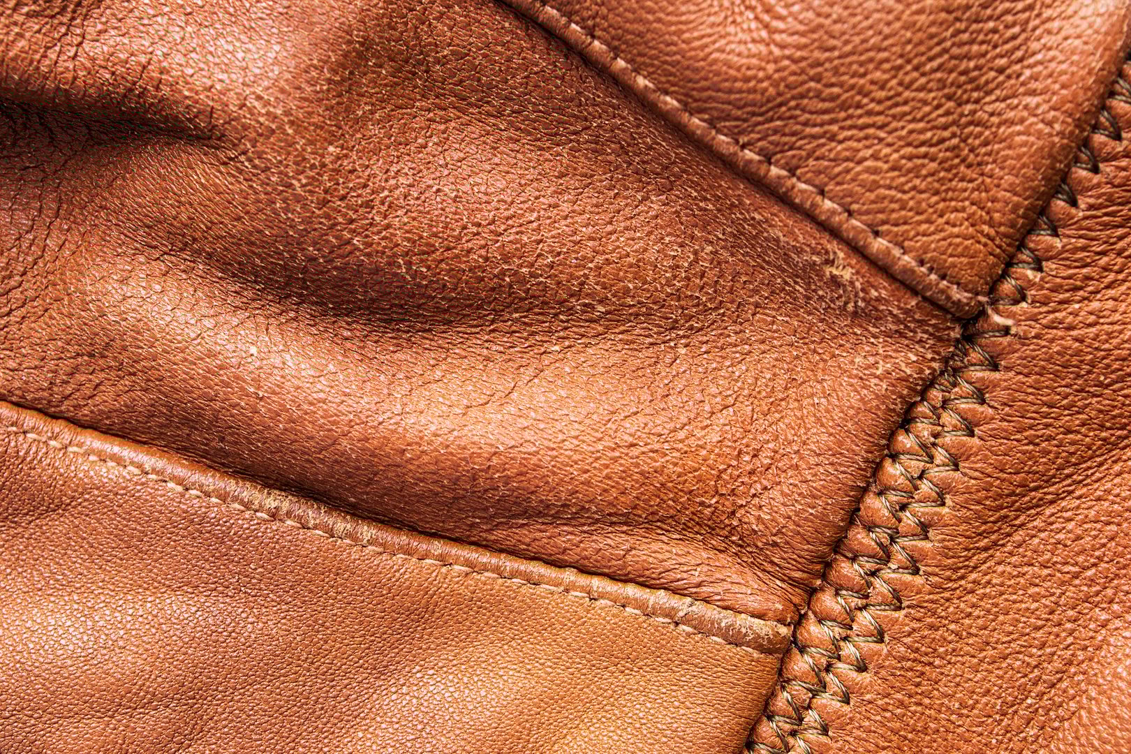 Old brown leather jacket details and stitches closeup as a background