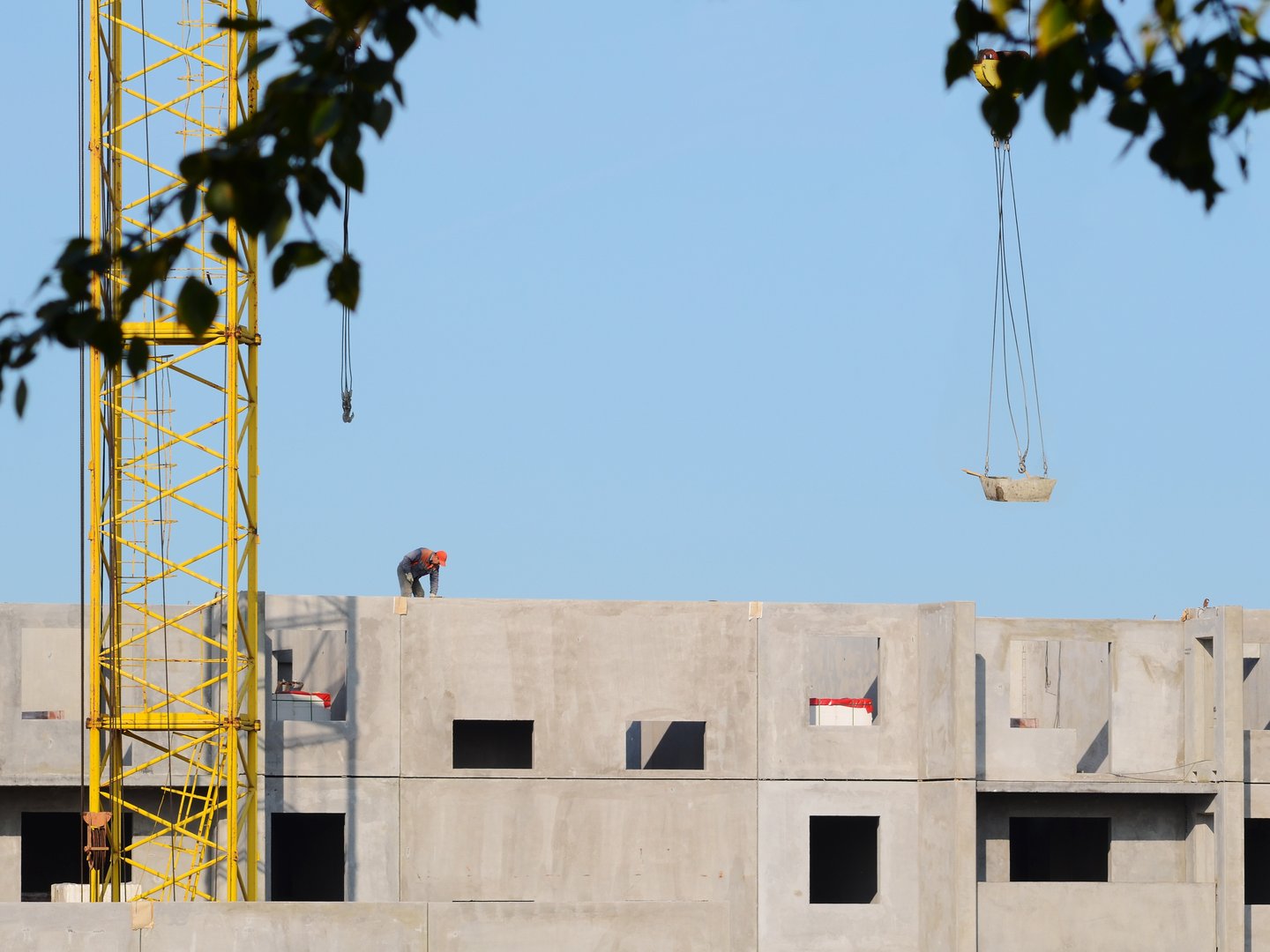 Chelyabinsk, RUSSIA - 2 September, 2018. Yellow crane building a panel house. An asian workers without a hard hat - a violation of safety regulations